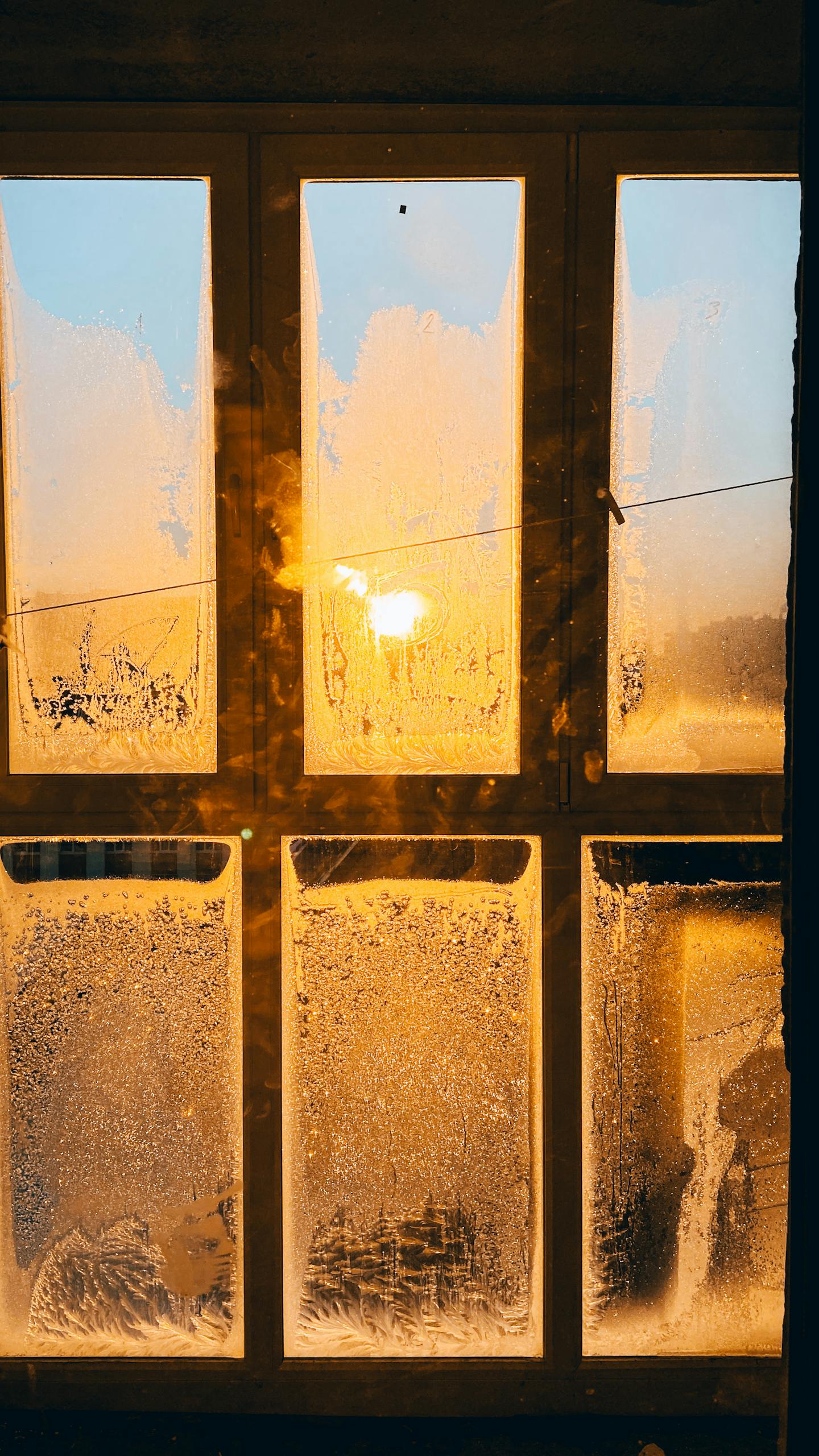 A frosty window glowing with warm sunlight during a winter sunrise, creating a beautiful contrast.