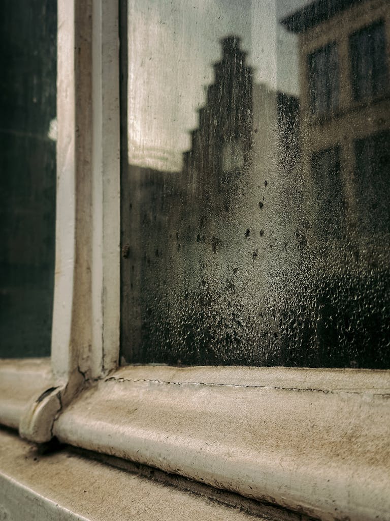 A moody view of Flemish architecture through a fogged-up window in Bruges, Belgium.