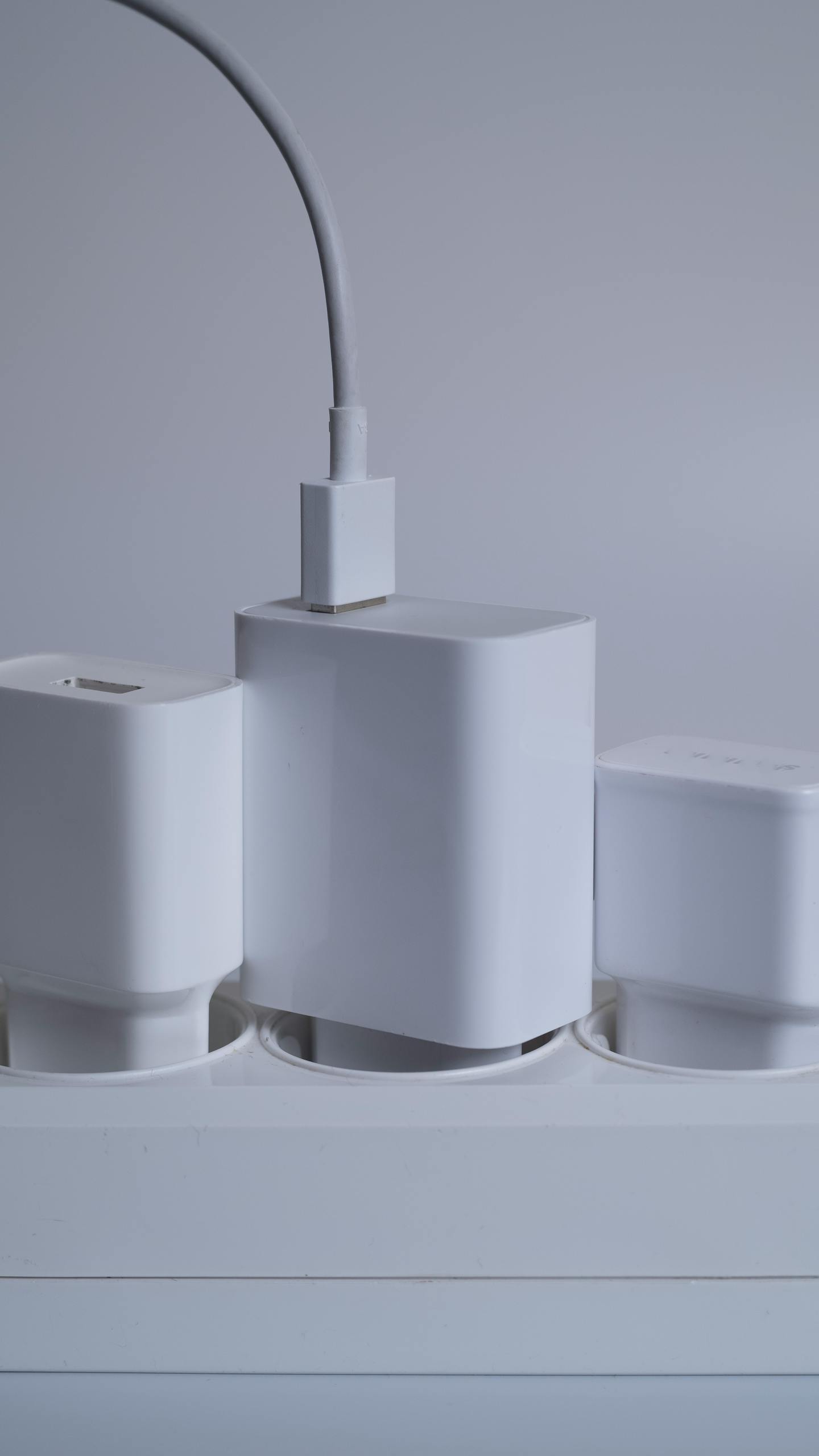 Contemporary white power adapters arranged neatly on a power socket bar.