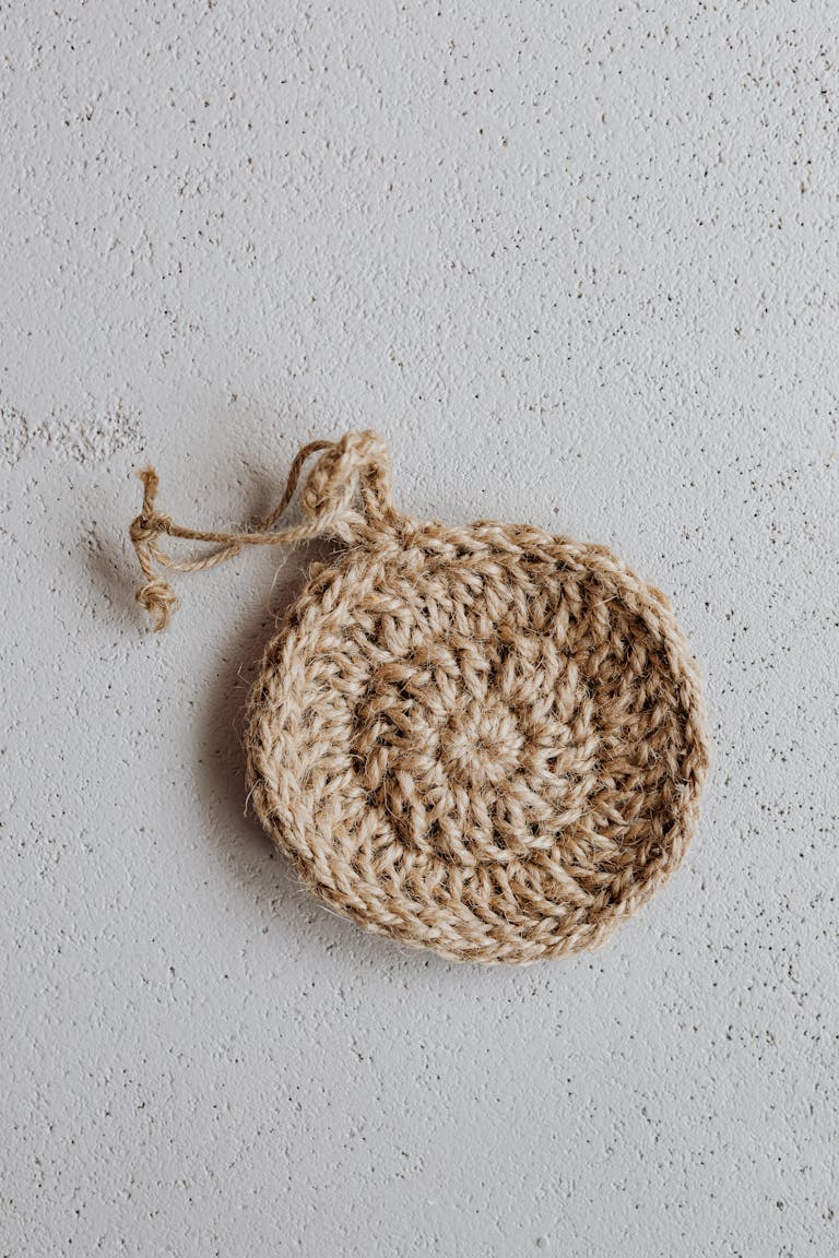 Eco-friendly handmade jute scrubber on textured surface, minimal aesthetic.