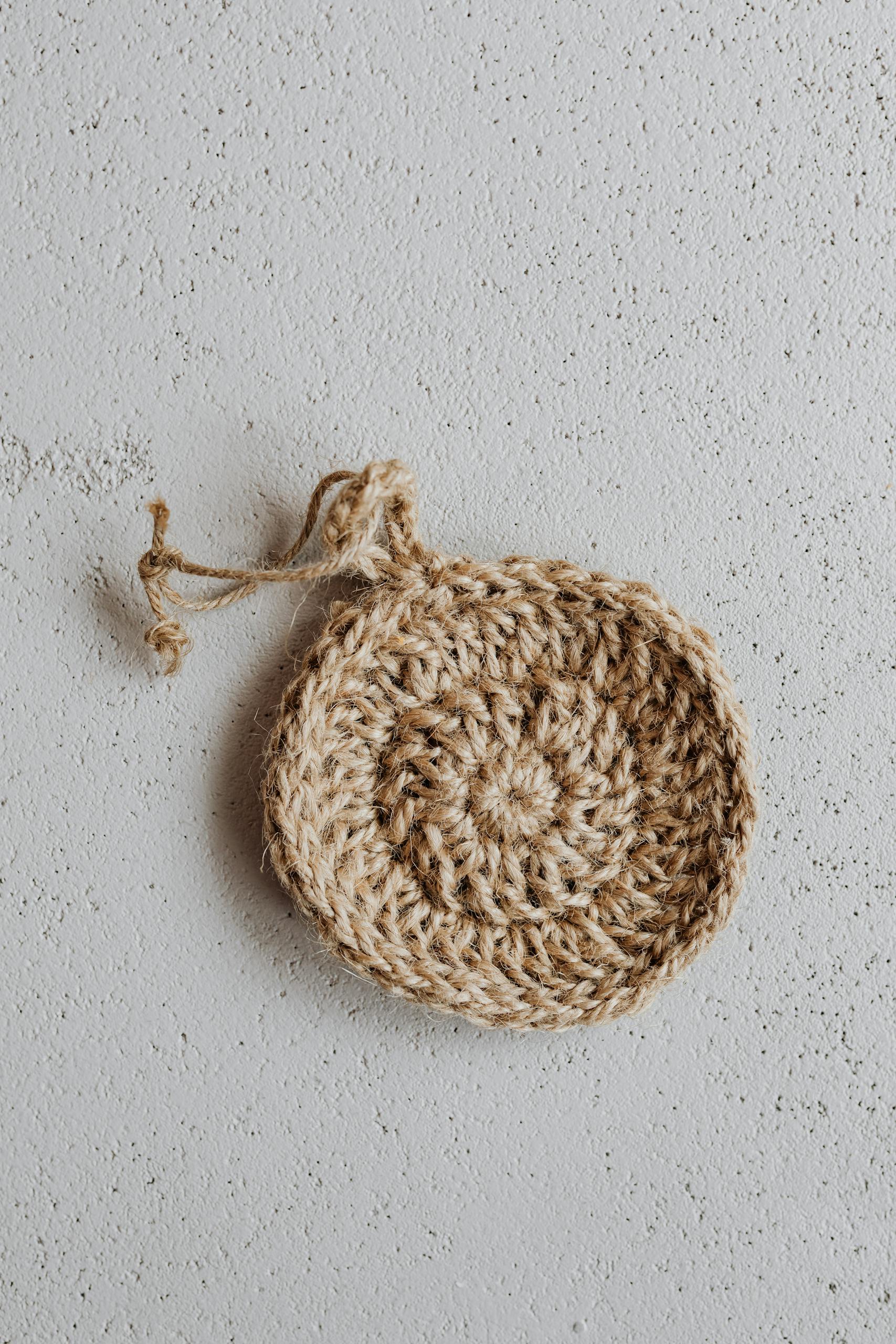 Eco-friendly handmade jute scrubber on textured surface, minimal aesthetic.