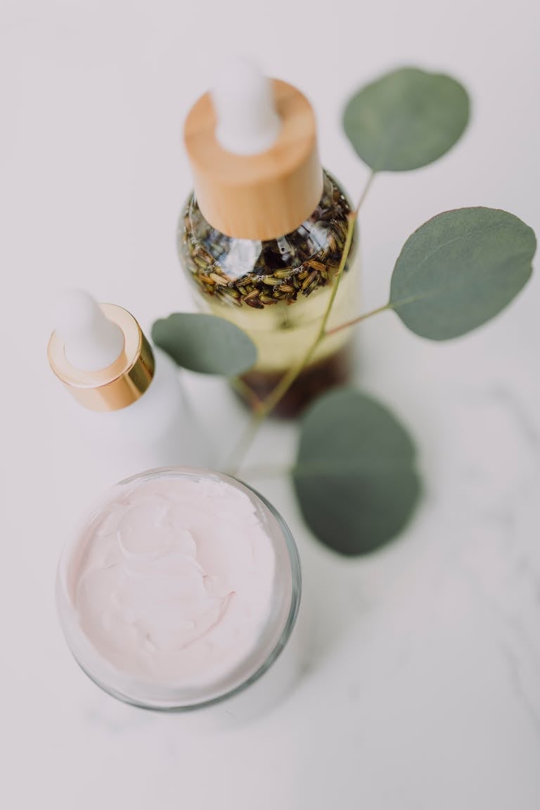 Minimalist skincare display featuring creams and oils with eucalyptus leaves.