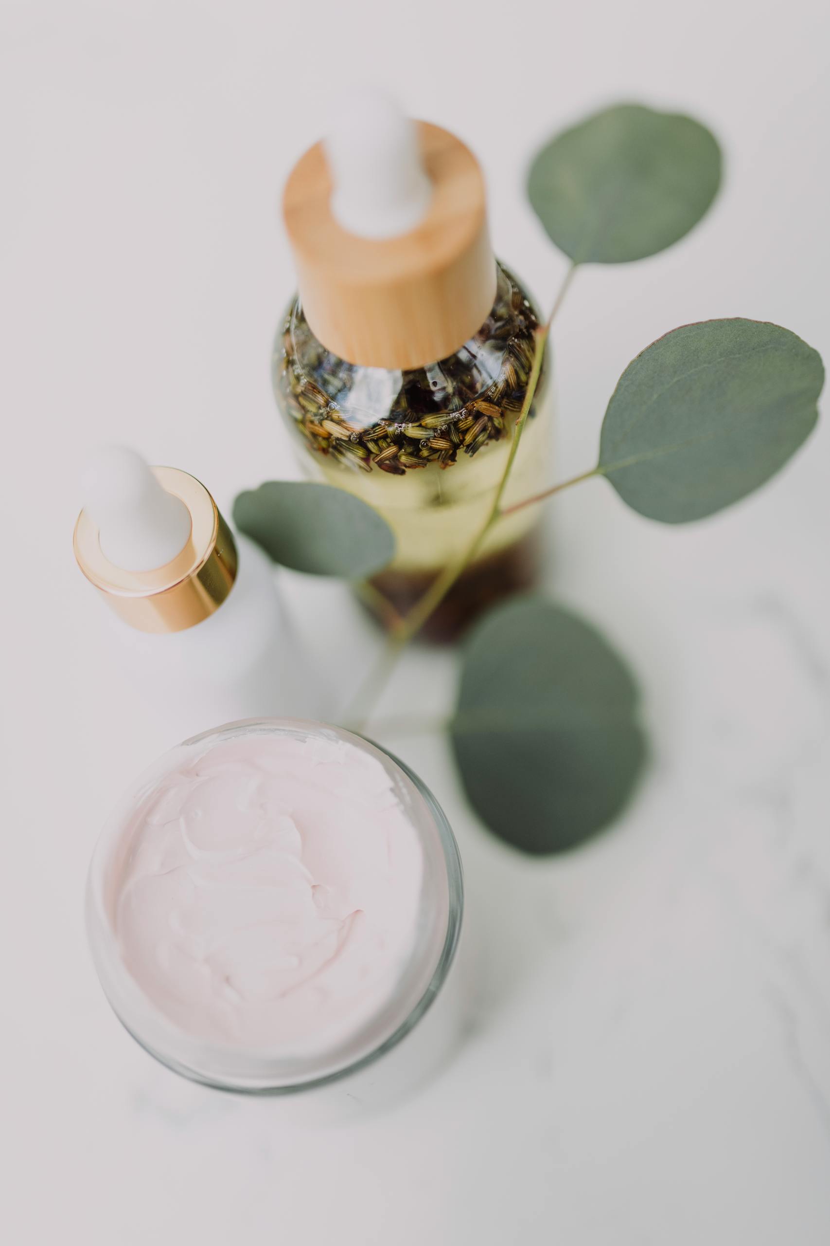 Minimalist skincare display featuring creams and oils with eucalyptus leaves.